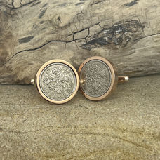 Pair of handmade coin cufflinks crafted from vintage British coins, displayed on textured sandstone