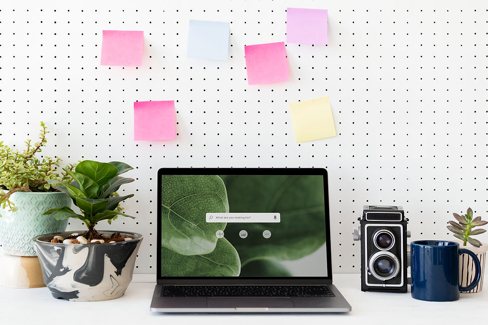 Laptop screen with post it notes on a peg board with plants to depict prodcutivity in a natural office setting.