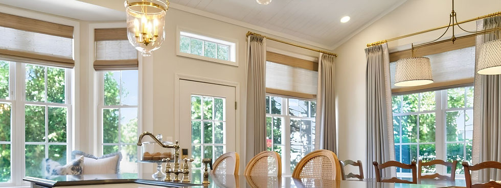 Perfect white paint combination in kitchen and great room with large Colonial style windows with gold rods and greyish blue curtains in summer with large lantern style pendant lights