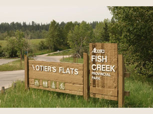 Votier's Flats Sign at the entrance to Fish Creek Provincial Park. It is summer with a wildfire smoke haze in the sky.