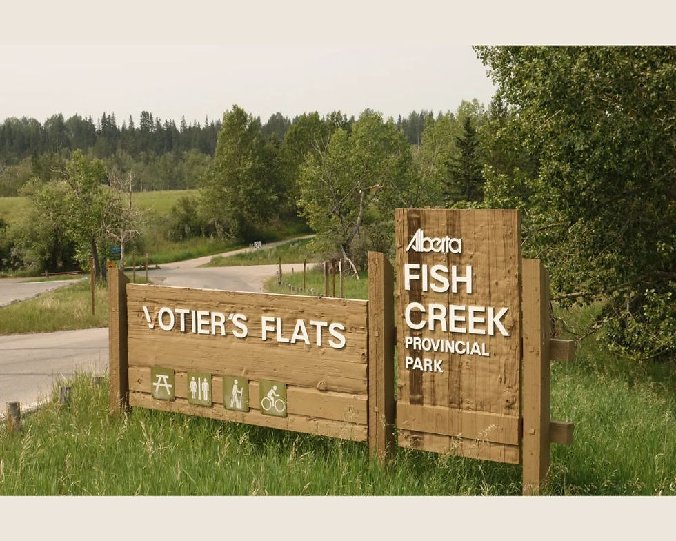 Votier's Flats Sign at the entrance to Fish Creek Provincial Park. It is summer with a wildfire smoke haze in the sky.