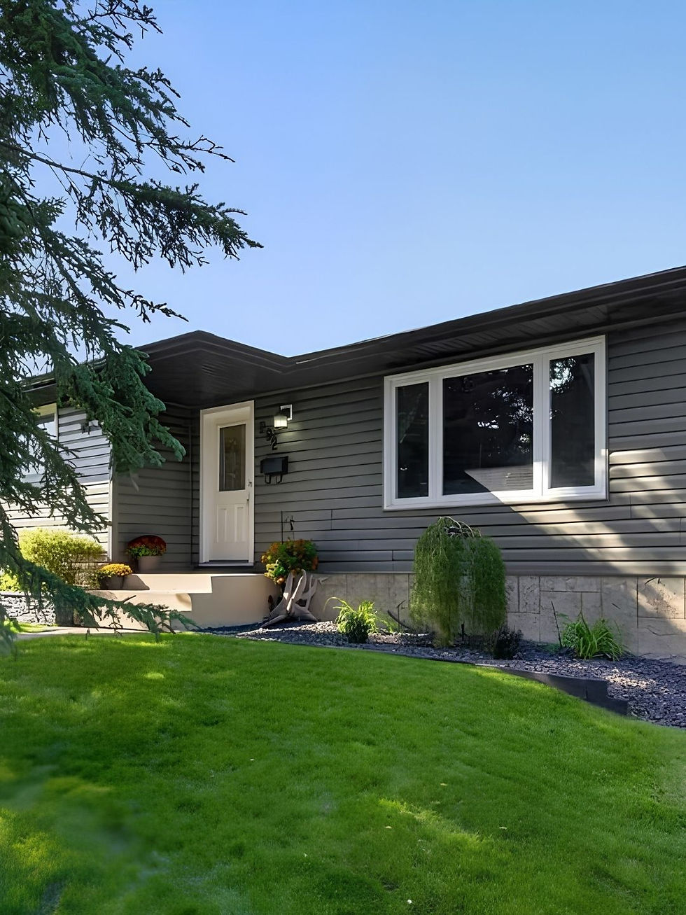 Grey siding with white trim, bungalow in summer with new sod lawn.