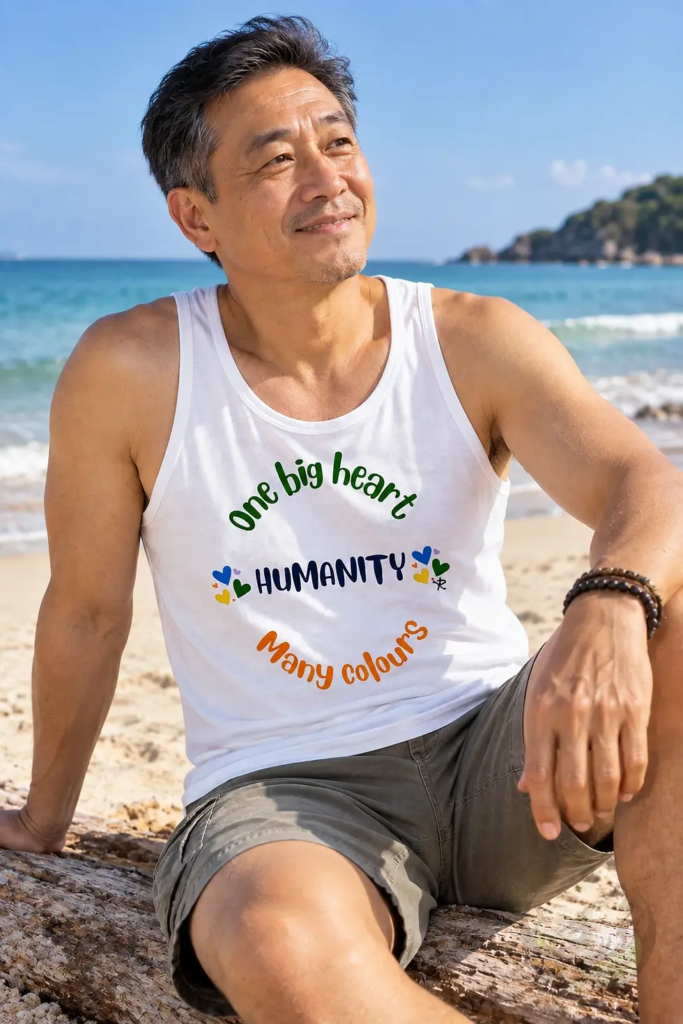 White mens tank top with One Big Heart Humanity Many Colours design worn by man on a beach