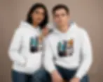 Couple wearing white unisex hoodies featuring colourful Pixels Cat artwork in a clean studio portrait.