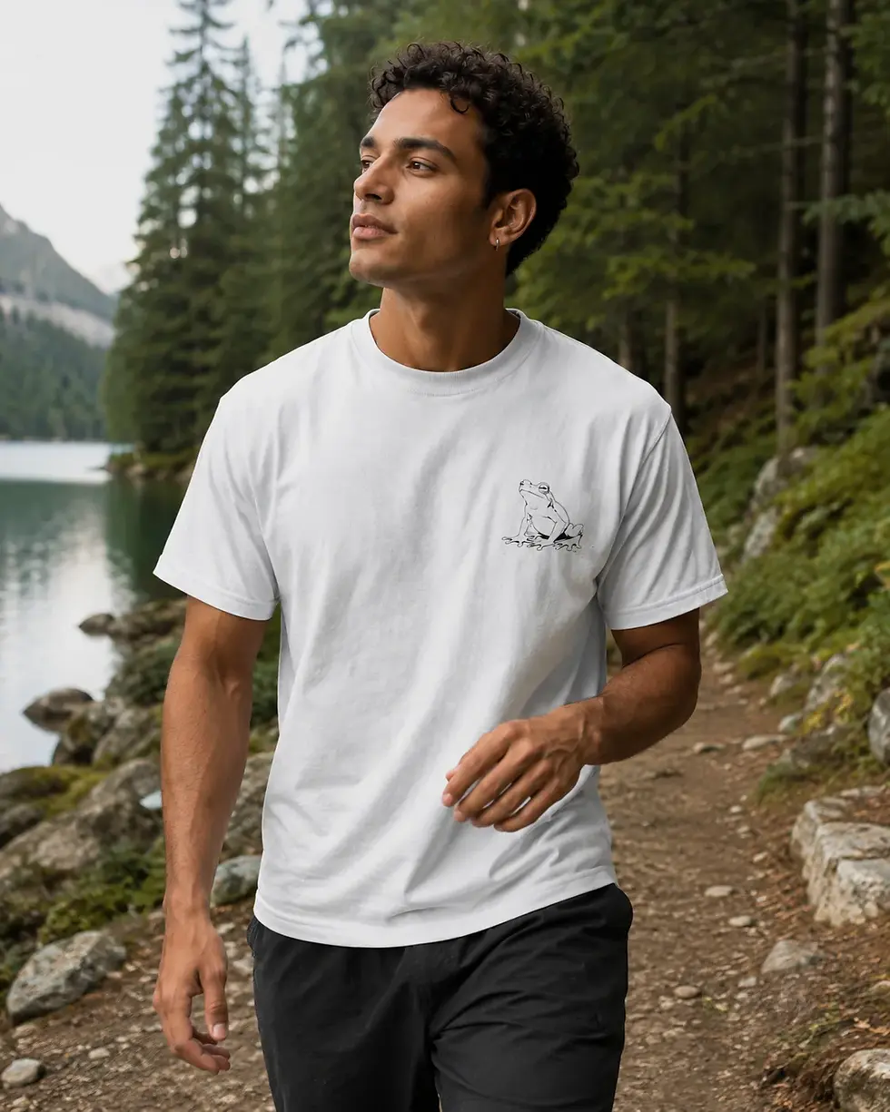 Man hiking near forest lake wearing white unisex frog Elegant Lines shirt with minimalist animal artwork