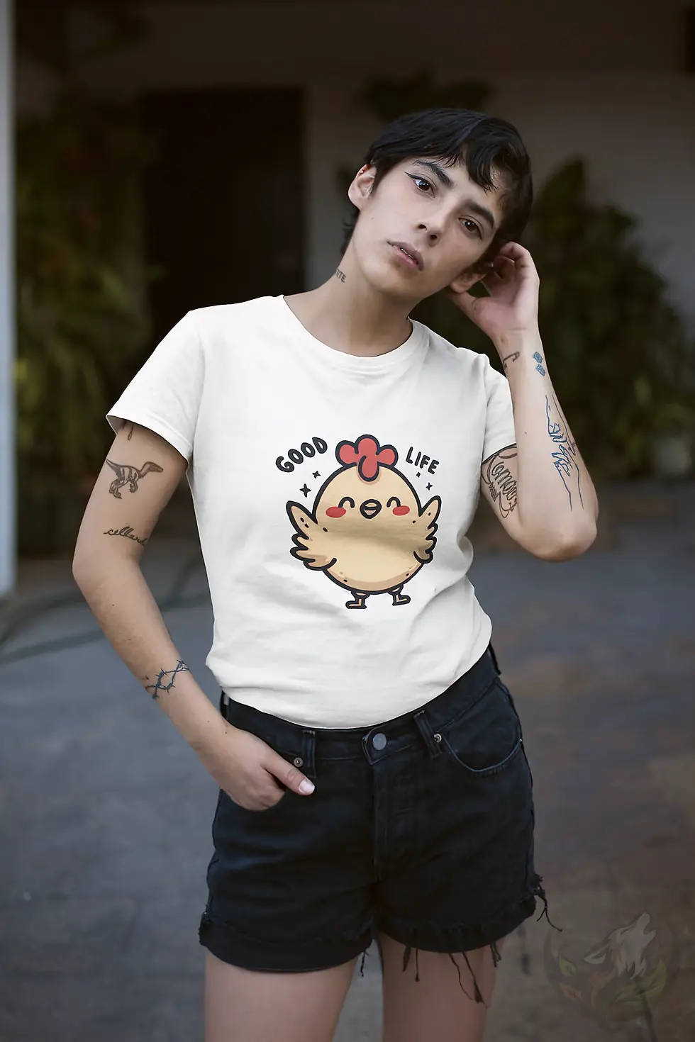 Thumbnail: Woman wearing a white good life shirt with a cartoon chicken and “Good Life” text, standing outside