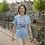 Thumbnail: Light blue fitted tee with Cute Dog Vegan Life design worn while walking along a sunny canal with historic buildings.