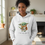 Thumbnail: Woman wearing a white "Vegan you must be" Yoda hoodie in a bright setting near a fireplace