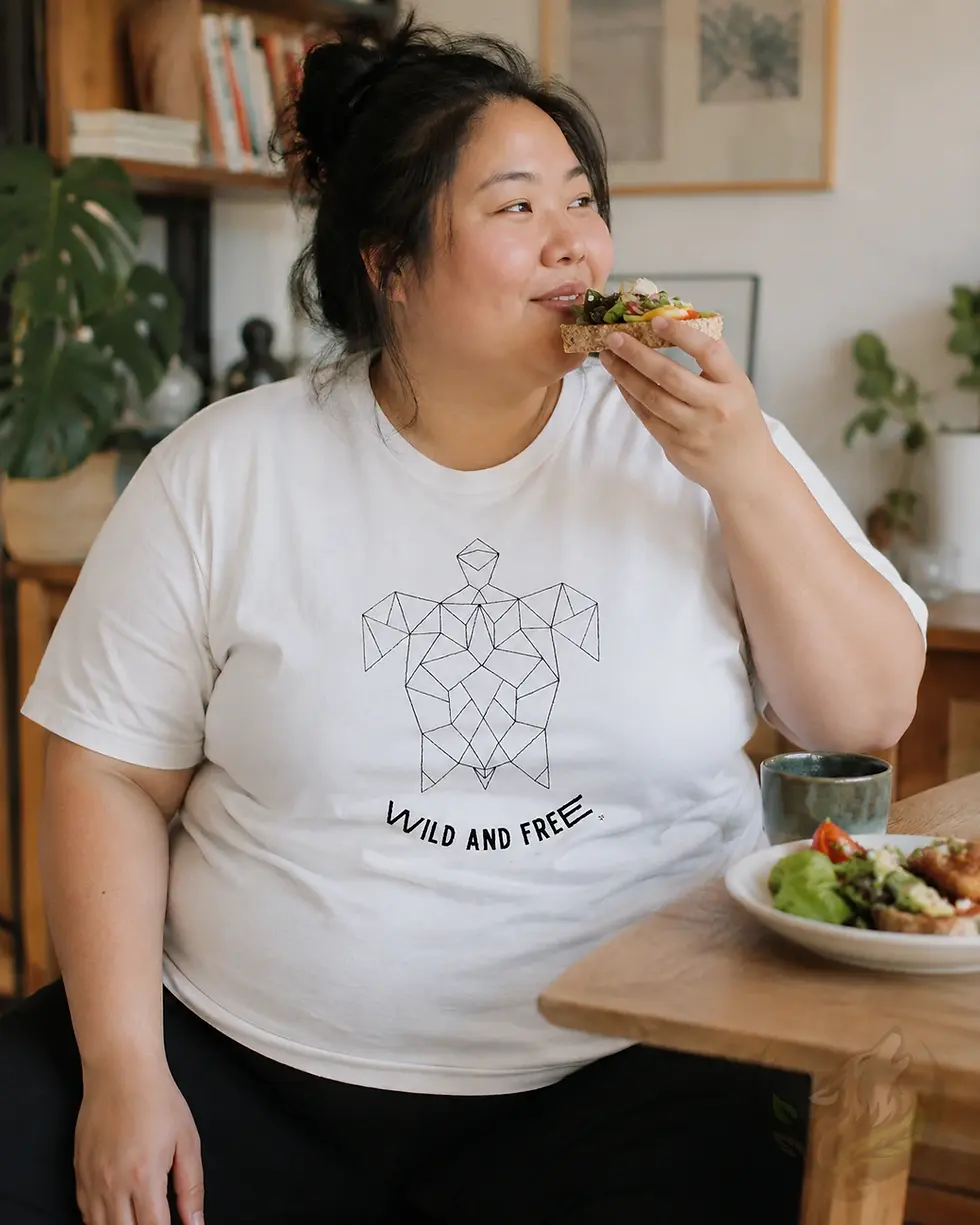 Plus size woman wearing a white shirt with geometric turtle design and Wild and Free text