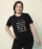 Black shirt with colorful “I just want to” vegan quote design, worn by a woman against a soft indoor backdrop.