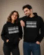 Couple wearing black unisex No Reason To Repeat Yourself hoodies in a clean studio portrait.