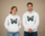 Couple wearing matching white hoodies featuring a colorful pixel-style butterfly design in a studio portrait