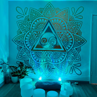 Mandala mural illuminated with blue light, with seven crystal sound bowls arranged for a sound healing class.