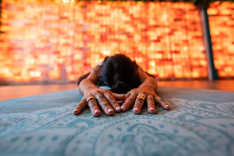 Person meditating in front of Himalayan salt wall for relaxation and respiratory health.