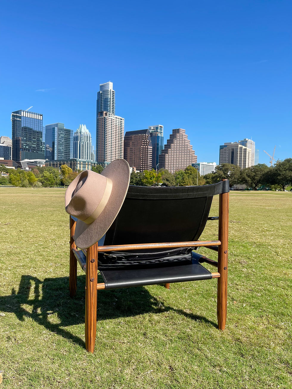 Thumbnail: Black leather safari chair in a park with the austin skyline in the background. A cowboy hat is hanging from the back.