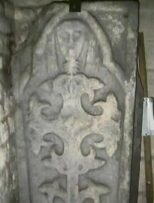 A tomb lid depicting a head and cross