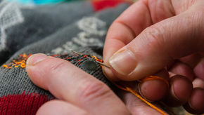 An item of clothing being repaired by someone with a needle and thread