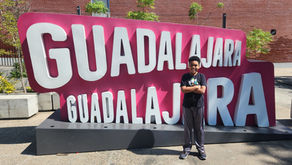 A male child standing in front of a sign that says "Guadalajara."