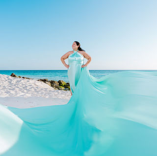 Woman wearing a mint green flying dress during a professional Aruba beach photoshoot.