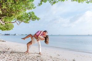 Playful couple dancing and dipping on the shoreline at Eagle Beach Aruba during a fun couples photoshoot by island photographer Edrxck