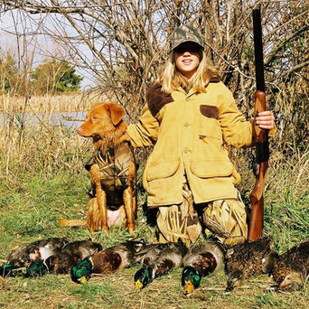 Young girl duck hunting with a dog.