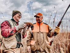 upland hunters holding a wild rooster pheasant