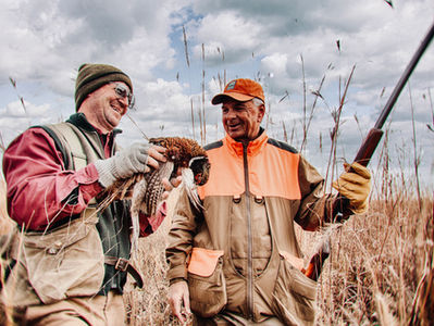 upland hunters holding a wild rooster pheasant