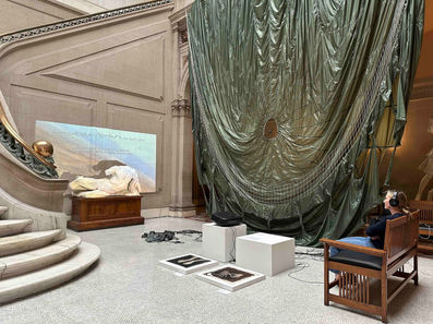 Installation view of ‘Untethered’ (2024) in the main court at Maryland Institute College of Art, Baltimore, MD, USA. Decommissioned, model T-10, U.S. military personnel parachute with severed suspension lines, detached harness with risers, 550 para-cord. High-definition video projection, stereo soundtrack, 7 min 26 sec. Parachute diameter: 35 feet. Harness dimensions: 30 x 30 inches (excluding suspension lines)