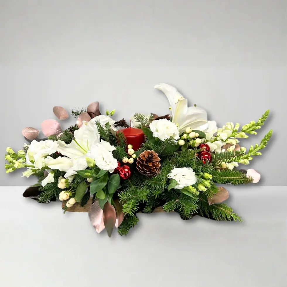 Elegant white Christmas centerpiece with lilies, candle, pinecones, berries, festive greenery and champagne eucalyptus.