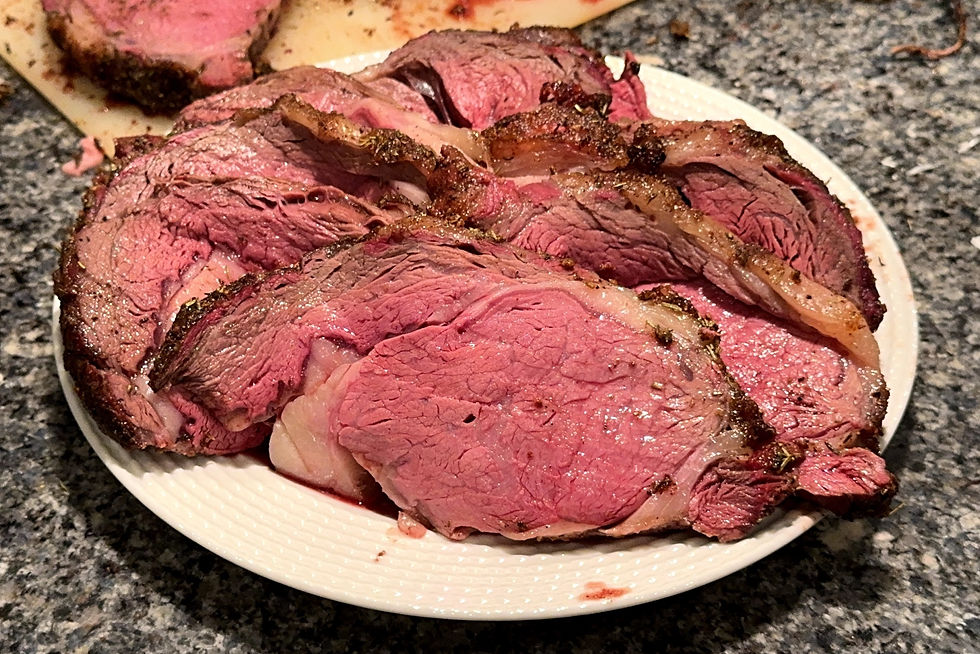 Slices of juicy, medium-rare roast beef on a white plate, set on a granite countertop. The beef shows a mix of pink hues and crispy edges.