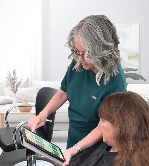 Dianne Sitar showing a client their dermascope scalp imaging results on a tablet at her Laconia NH hair loss studio