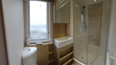 Bathroom with toilet, shower, and window; interior view of caravan.