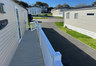 Caravan park pathway with holiday homes in residential area on a sunny day.