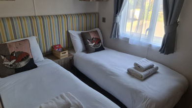 Twin beds in a modern bedroom with pillows and a window.