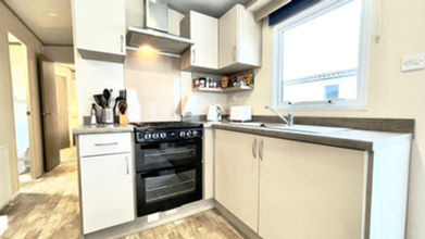 Modern kitchen with appliances and cabinets; light decor with countertop. Holiday Homes For Sale