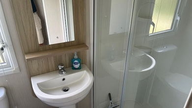 Small bathroom inside a caravan with sink and shower unit; clean.