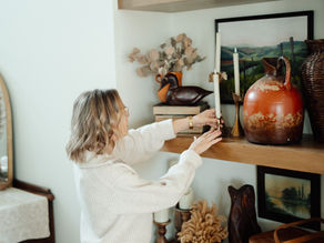 Woman adjusting decor items on a shelf.