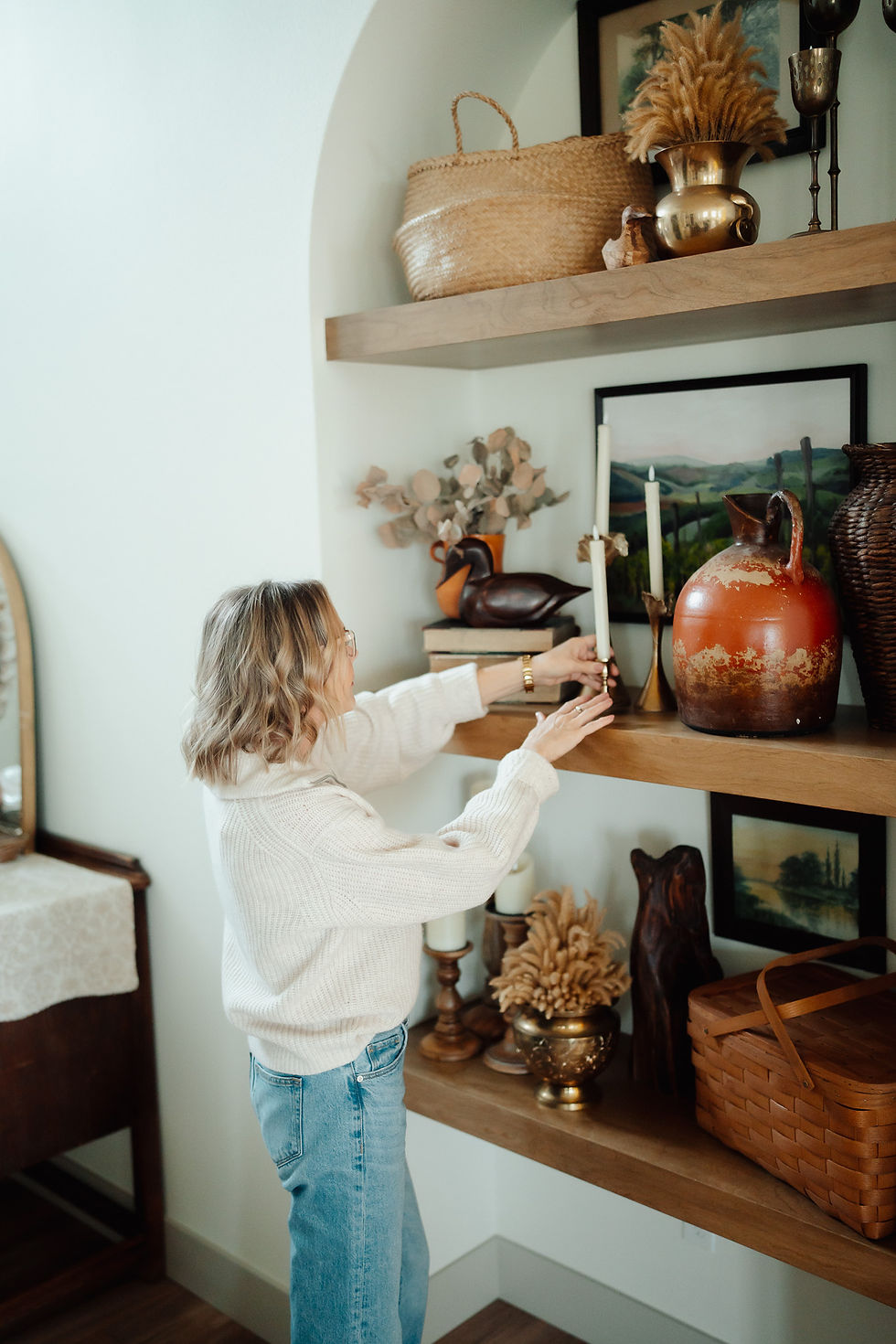 Woman adjusting decorations on a shelf.