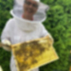 Imker Thomas Völcker mit Honigwabe im Schutzanzug