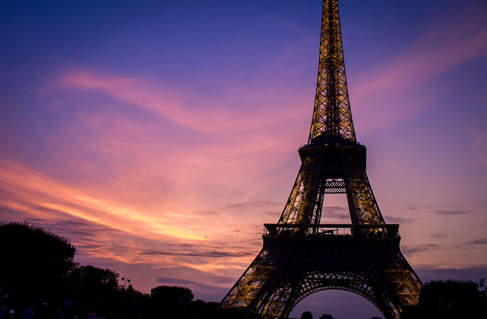 Late summer 2017, this shot was taken as the sun set behind the Eiffel Tower in Paris, France. Wisps of clouds painted violet and orange streaked a deep purple sky as the lights of the tower turned on.