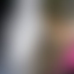 Una ragazza con casco e muta da torrentismo sorride davanti a una cascata durante un percorso di canyoning per principianti con Alp Adventure.