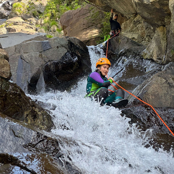 una ragazza effettua uno scivolo naturale nel rio Prialunga in Liguria durante una discesa di torrentismo