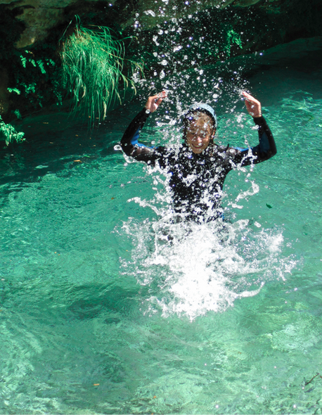 una ragazza gioca con l'acqua cristallina del Rio Barbaira in Liguria durante una discesa di canyoning
