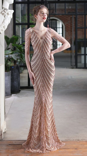 A model poses in a boutique, wearing the rose gold Cocoa Scallop plunge neck scallop sequinned detail maxi dress - perfect for special events or evening-wear.