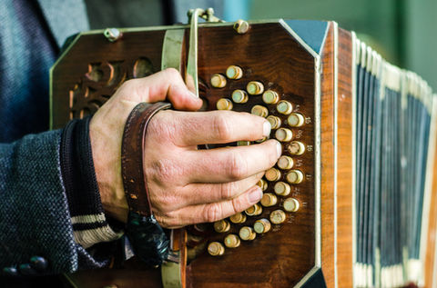 A street artist playing bandoneon, traditional tango instrument, on Caminito street in La