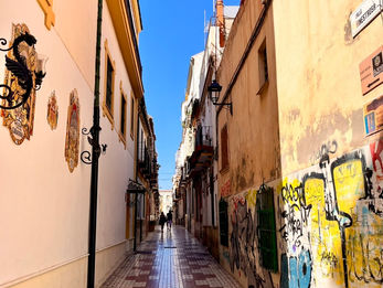 Schmale Gasse mit Graffiti und gemustertem Pflaster.
