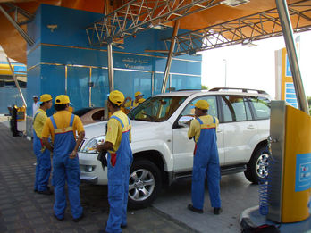 Mitarbeiter in blauer Arbeitskleidung an einem weissen SUV in Dubai.