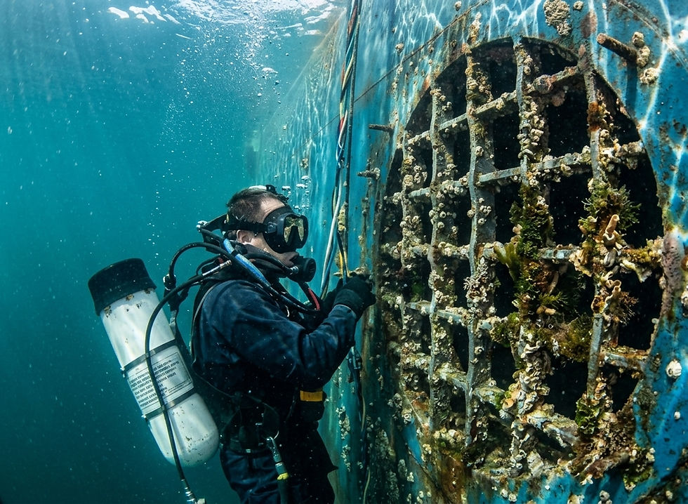 Diver cleaning marine growth from boat's running gear