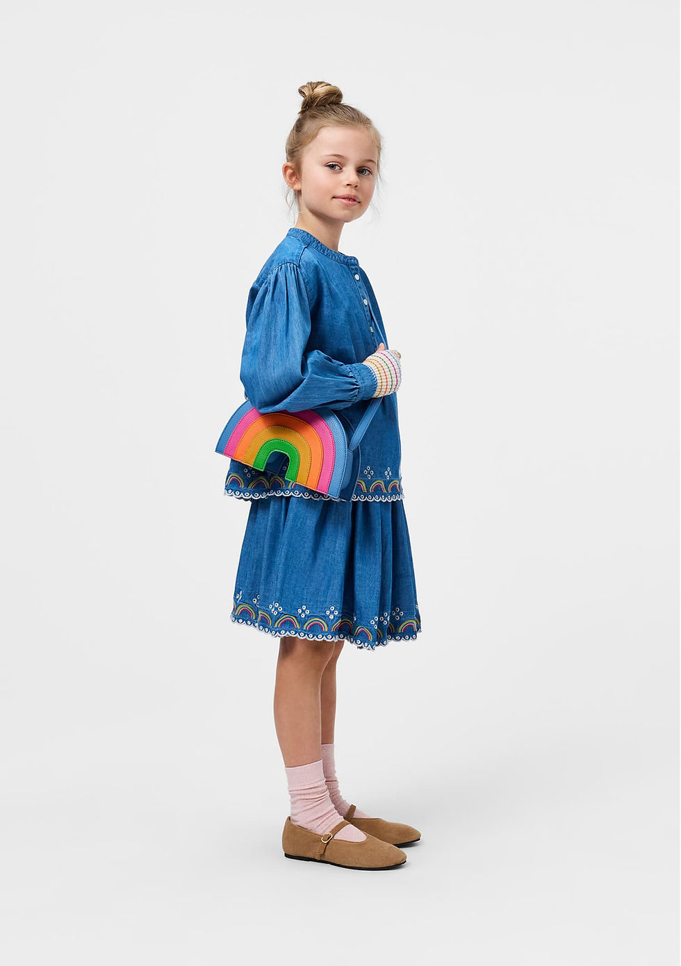 Child standing and wearing the rainbow bag crossbody with a denim outfit.