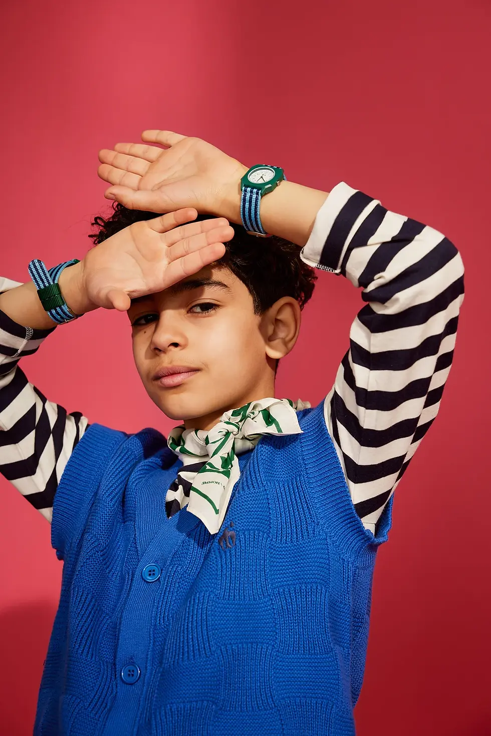 Child wearing the A Day on Earth watch, posing playfully against a red background.